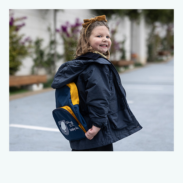 niña sonríe con mochila del colegio Oak House School
